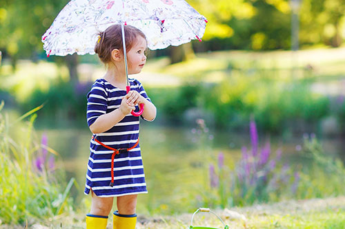 child with umbrella and wearing gumboots